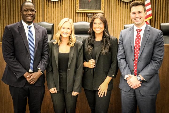 Group of people staind ing a courtroom smiling